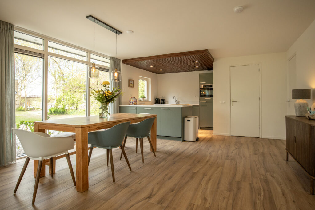 Interior of a midcentury holiday house with a chimney and an integrated house extension, interior with green kitchen, De Cocksdorp, Texel, Netherlands
