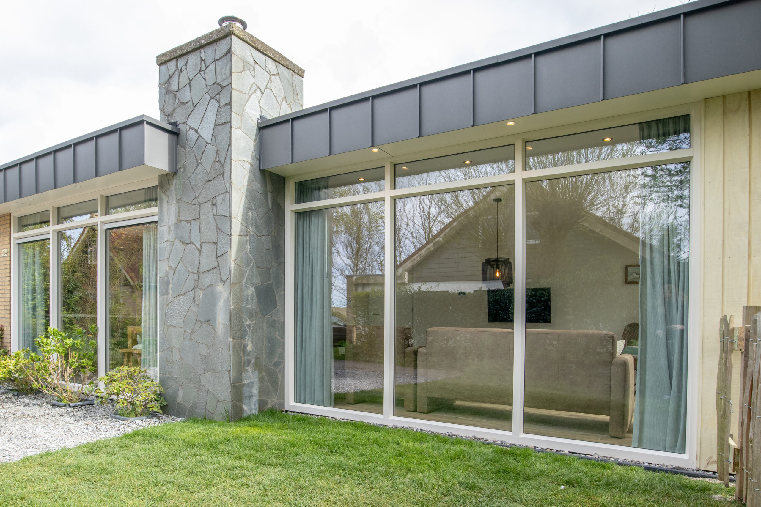 Facade of midcentury holiday house with a chimney and an integrated house extension, natural stone facade, wooden facade